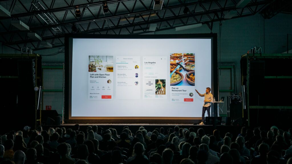 Une personne présente un PowerPoint sur scène devant un public